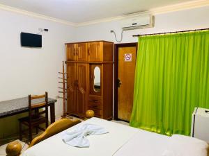 Una habitación con una cortina verde y una cama. en Hotel Universitário Goiatuba, en Goiatuba