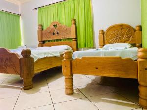 2 camas en una habitación con cortinas verdes en Hotel Universitário Goiatuba, en Goiatuba