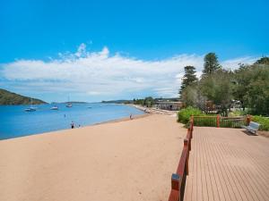 a sandy beach with boats in the water at Bella Mare - 2 Bedroom Ocean View Terrace Apt in Ettalong Beach