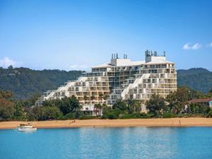 a large building on the beach next to the water at Hinterland Luxury - 1 Bedroom Hinterland View Apt in Ettalong Beach