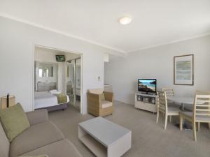 a living room with a couch and a bedroom at Hinterland Luxury - 1 Bedroom Hinterland View Apt in Ettalong Beach