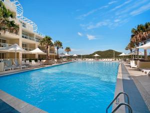 a swimming pool at a resort with chairs and umbrellas at Hinterland Luxury - 1 Bedroom Hinterland View Apt in Ettalong Beach