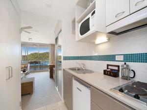 una cucina con armadi bianchi e vista sull'oceano di Ocean Panorama - 1 Bedroom Oceanview Apt a Ettalong Beach