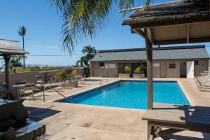 a swimming pool with tables and chairs next to a building at KH 116 Everything You Need For Your Home Away From Home in Kihei