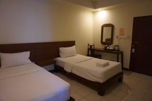 a hotel room with two beds and a mirror at The One Residence in Udon Thani