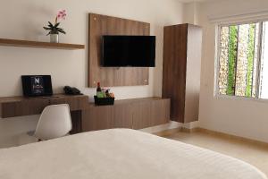 a bedroom with a bed and a flat screen tv at NOA Hotel Boutique in Tuluá
