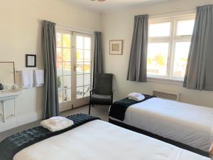 a bedroom with two beds and a chair and a window at Ranfurly Hotel in Ranfurly