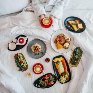 a person laying on a bed with plates of food at Novotel Sydney Olympic Park in Sydney