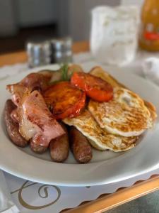 a plate of breakfast food with eggs sausage and tomatoes at Golden Harvest Motor Inn Moree in Moree