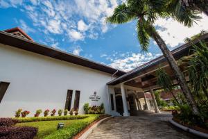 a building with a palm tree in front of it at Sabah Hotel in Sandakan