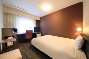 大阪市にあるダイワロイネットホテル大阪四ツ橋のベッドとデスクが備わるホテルルームです。