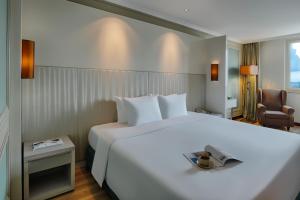 ein Hotelzimmer mit einem großen weißen Bett und einem Stuhl in der Unterkunft Windsor Plaza Hotel in Ho-Chi-Minh-Stadt