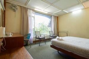 a bedroom with a bed and a desk and a window at Bellevue The Penang Hill Hotel in Ayer Itam