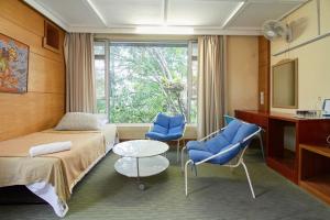 a hotel room with two beds and two blue chairs at Bellevue The Penang Hill Hotel, Bukit Bendera in Ayer Itam