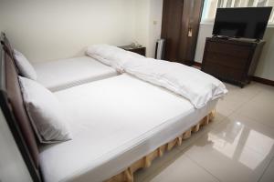 two twin beds in a room with a tv at Clear Water Bay Homestay in Nangan