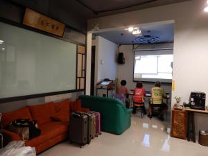 a living room with a couch and people sitting at a table at Happy Wing Guesthouse in Hualien City