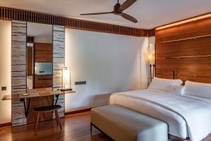 a bedroom with a bed and a table and a mirror at The Datai Langkawi in Teluk Datai
