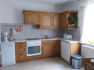 a kitchen with wooden cabinets and a white appliance at Haus Ingrid Ferienwohnung Vintage in Oberlungwitz