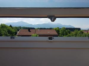 a window with a view of a house and mountains at Ferienwohnung-am-Chiemsee in Grabenstätt