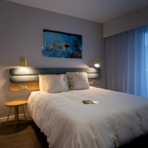 um quarto com uma grande cama branca e uma mesa em Hotel Libera Caen Colombelles em Caen