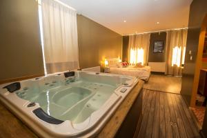 a large bath tub in the middle of a room at Hotel La Font Vineuse & Spa in Saint-Pierre-dʼArgençon