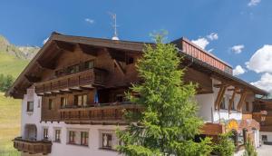 ein großes Gebäude mit einem Baum davor in der Unterkunft Arina Apartments in Samnaun