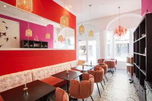 a restaurant with tables and chairs and a red wall at Hôtel Mademoiselle in Juan-les-Pins