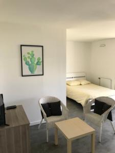 een slaapkamer met een bed en 2 stoelen en een tafel bij Studios de standing - Emeraude - Lille euralille in Lille