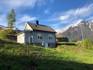 a small house on a hill with mountains in the background at Tunold Gård - Freden in Stryn