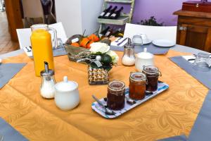 a table with a yellow table cloth with jars of honey and candles at Le Jardin des Roches in Moigny