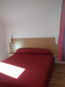 um quarto com uma cama vermelha com um cobertor listrado vermelho em CHALET DE BOIS MEAN em Les Orres