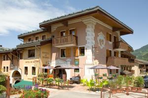 a building with tables and chairs in front of it at Hôtel du Bourg in Valmorel