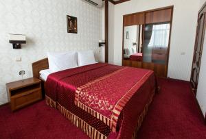a hotel room with a bed with a red blanket at Tatarstan Business-Hotel in Naberezhnyye Chelny