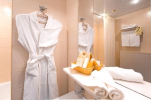 y baño con toallas blancas, lavabo y espejo. en Tatarstan Business-Hotel, en Naberezhnye Chelny