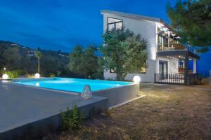 una villa con piscina di fronte a una casa di Entechnos Living a Città di Skiathos