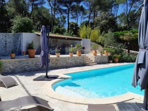 a swimming pool with an umbrella next to a house at VILLA LA LICORNE - Piscine privée, Spa, Tennis, Golf à 9km in Belcodène