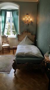 a bedroom with a large bed with a chandelier at Schloss Sennfeld - Schloss Akademie & Eventlocation - in Adelsheim