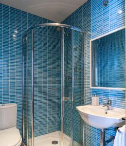 Baño de azulejos azules con aseo y lavamanos en Home Vejer, en Vejer de la Frontera