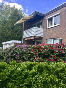 une maison en briques avec des fleurs roses devant elle dans l'établissement Ferienwohnung Liene, à Bad Zwischenahn