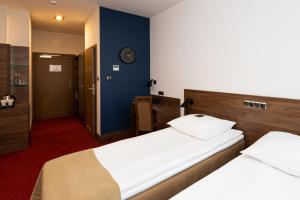 a bedroom with two beds and a clock on the wall at Hotel Olimp Business & Spa in Wejherowo