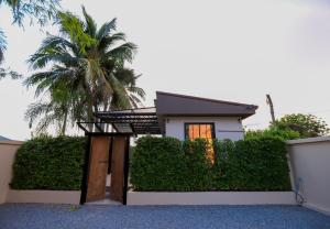 a house with a fence and a palm tree at Banamphur Pool Villa in Na Jomtien