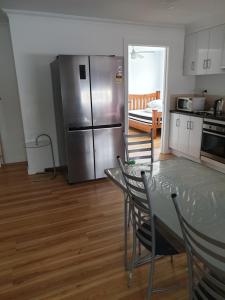 a kitchen with a table and a stainless steel refrigerator at DIANELLA Budget Rooms Happy Place to Stay in Perth