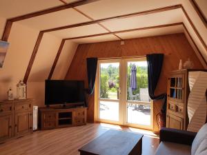a living room with a tv and a large window at Ferienhaus am Helenesee 5 in Frankfurt Oder