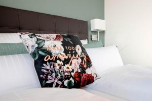 a pillow on a bed with a floral blanket at Zeitlos Boutiquehotel in Limburg an der Lahn