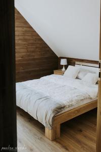1 dormitorio con 1 cama grande y pared de madera en Bobrowe Zacisze - domki letniskowe en Żarnowska