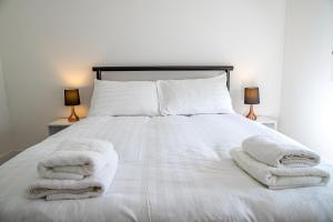 een wit bed met handdoeken erop bij Millburn Apartment in Inverness