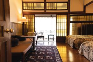 a bedroom with two beds and a desk and a table at Hotel Hanakoyado in Kobe