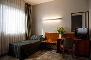 a hotel room with a bed and a desk with a television at Hotel Zone in Rome