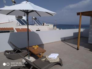 um pátio com uma mesa e um guarda-chuva no telhado em Fotaki's Home - Comfortable newbuilt 2 Bedroom Home, 20 meters from the sea em Kardamaina