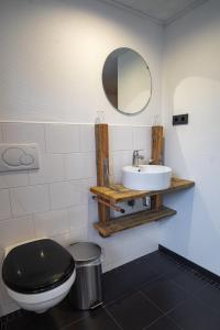 a bathroom with a black toilet and a sink at Pension de Wadvaarder in Midsland